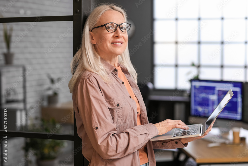 Mature female programmer working with laptop in office