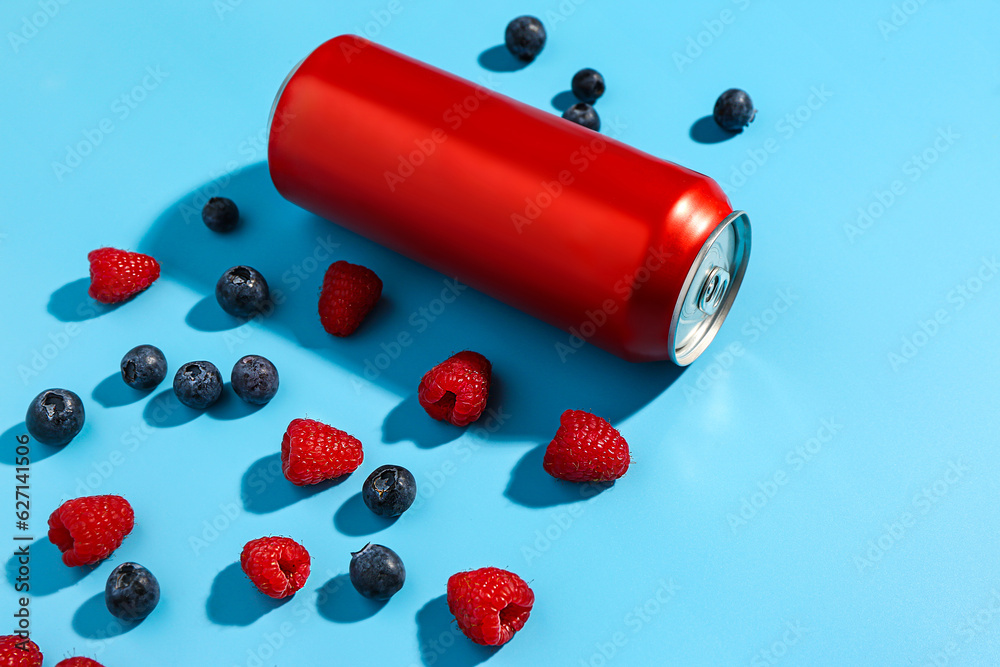 Composition with can of fresh soda and berries on blue background, closeup