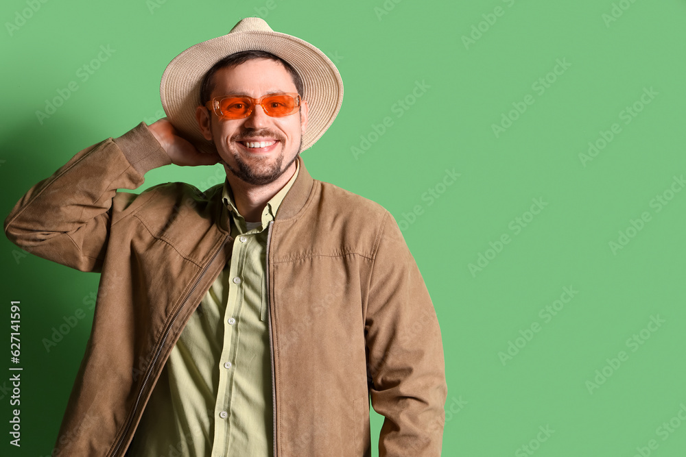 Handsome man in stylish sunglasses on green background