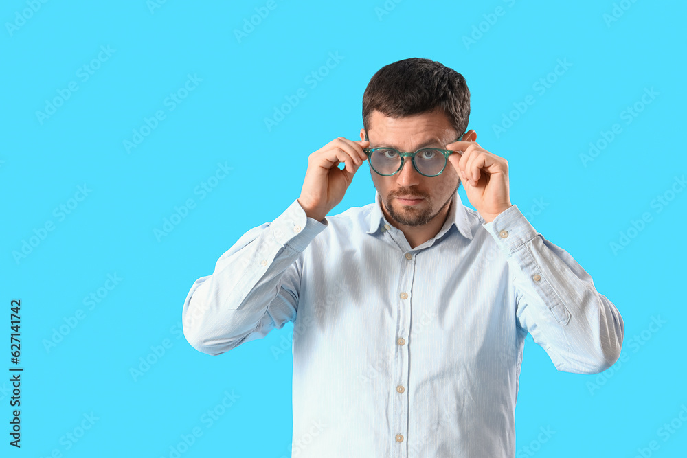 Handsome man in stylish eyeglasses on blue background