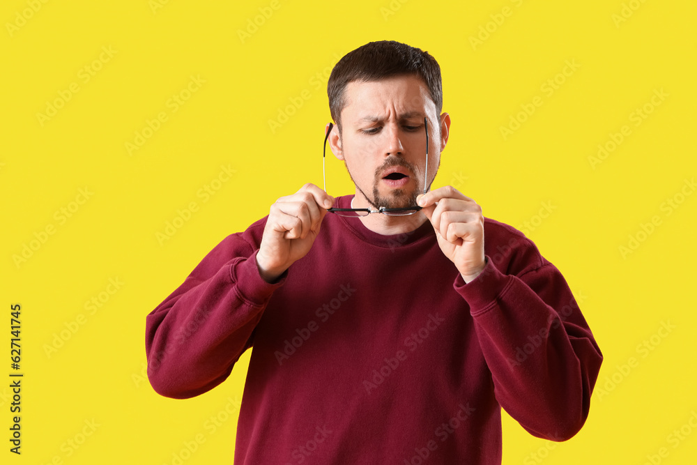 Handsome man with stylish eyeglasses on yellow background