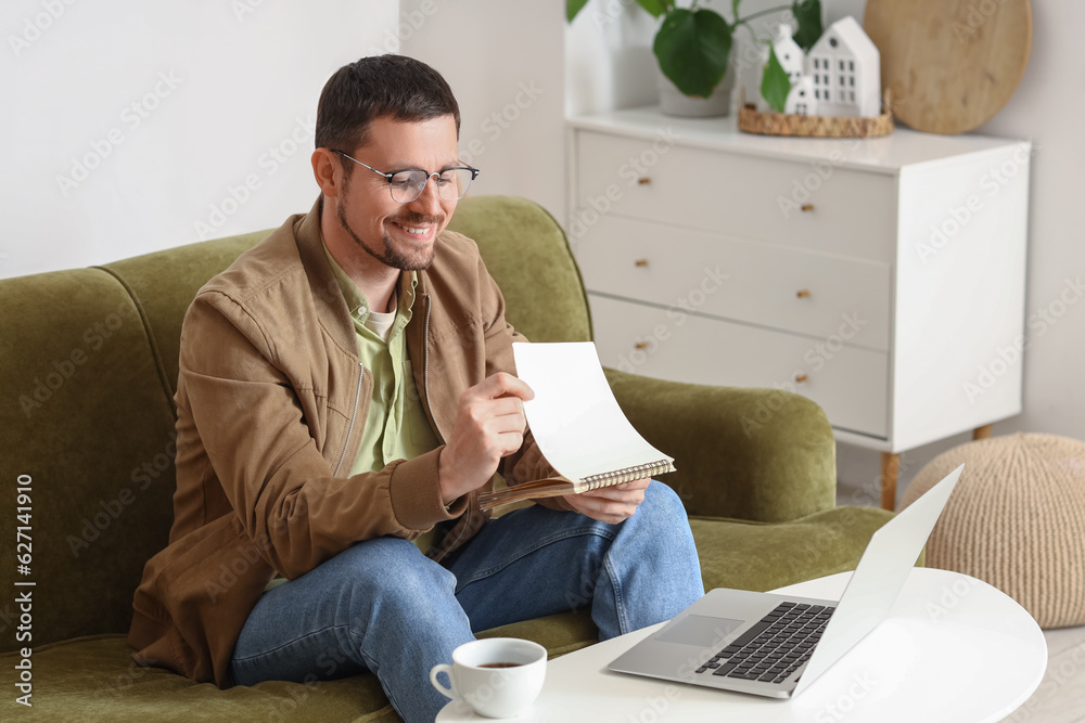 Handsome man in eyeglasses with notebook video chatting at home