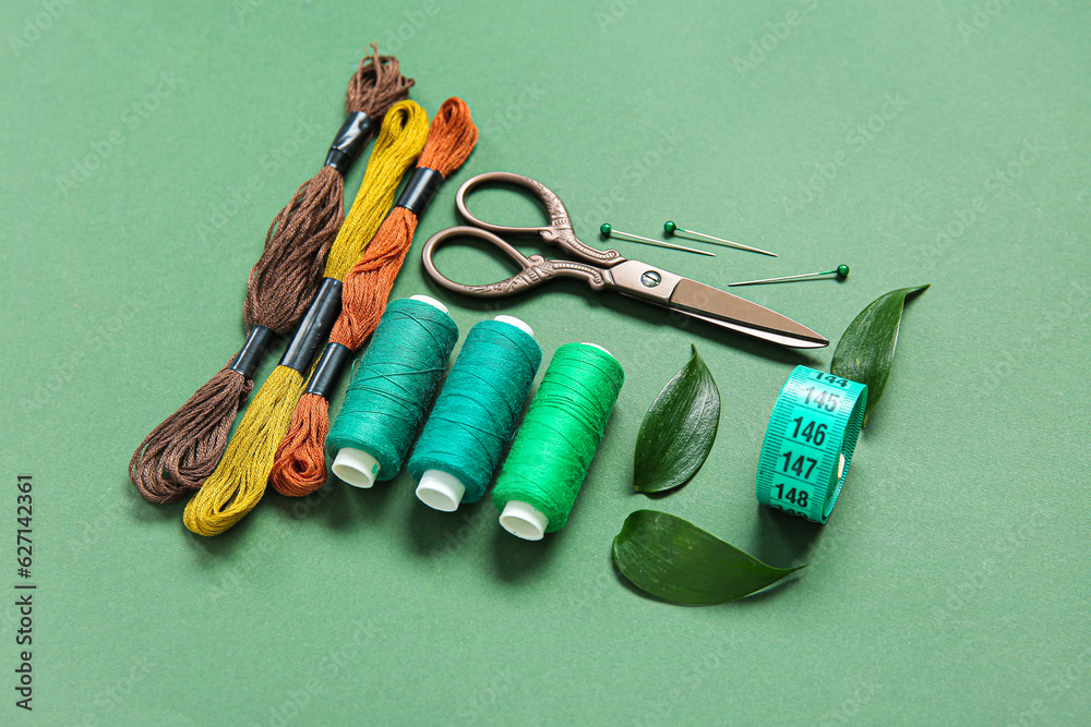 Set of different embroidery supplies on dark green background