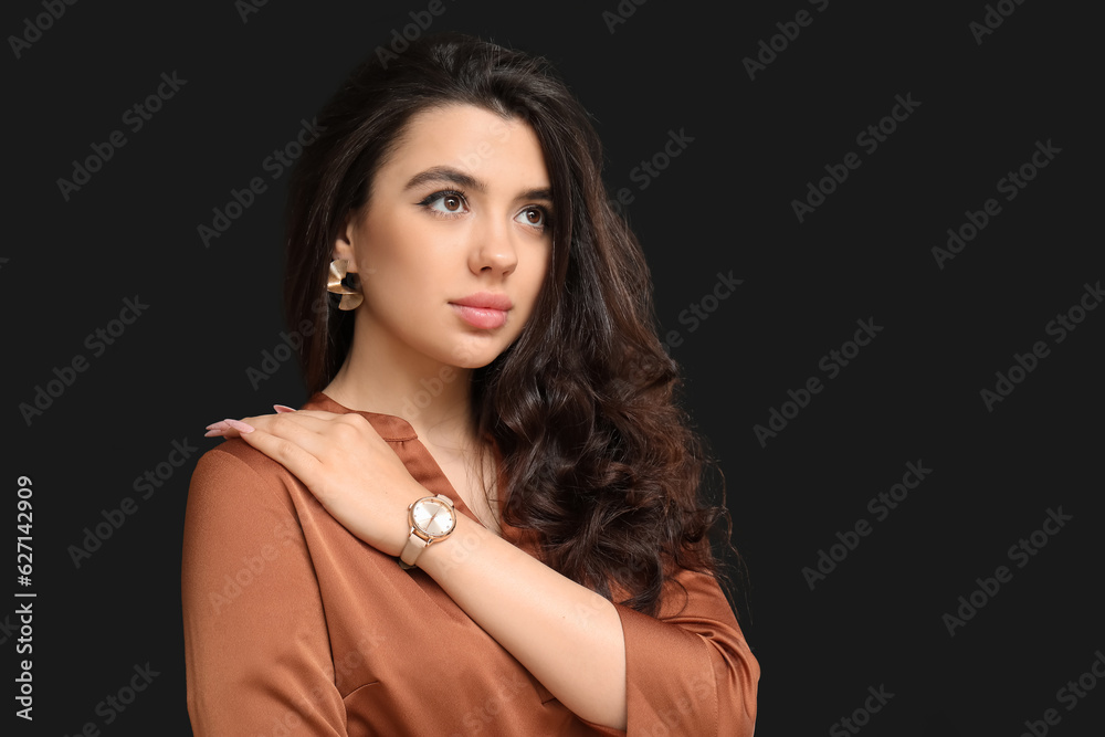 Elegant beautiful woman with wristwatch on black background