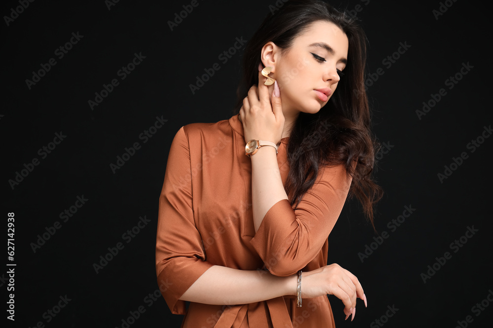 Elegant beautiful woman with wristwatch on black background