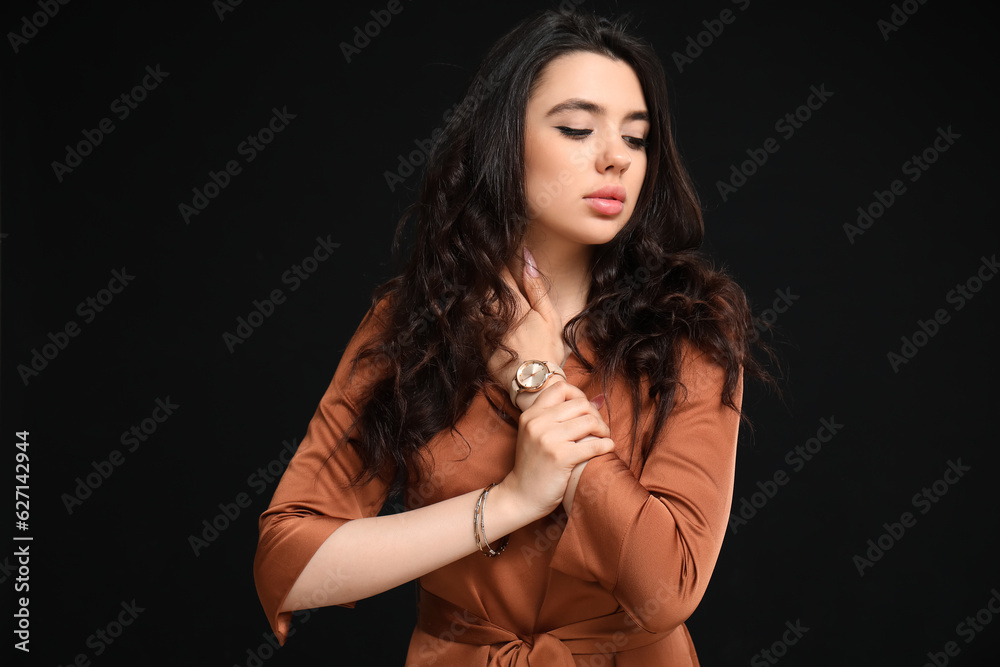 Elegant beautiful woman with wristwatch on black background