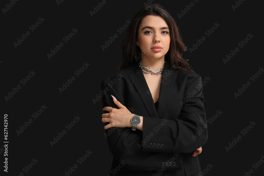 Beautiful young woman with wristwatch on black background