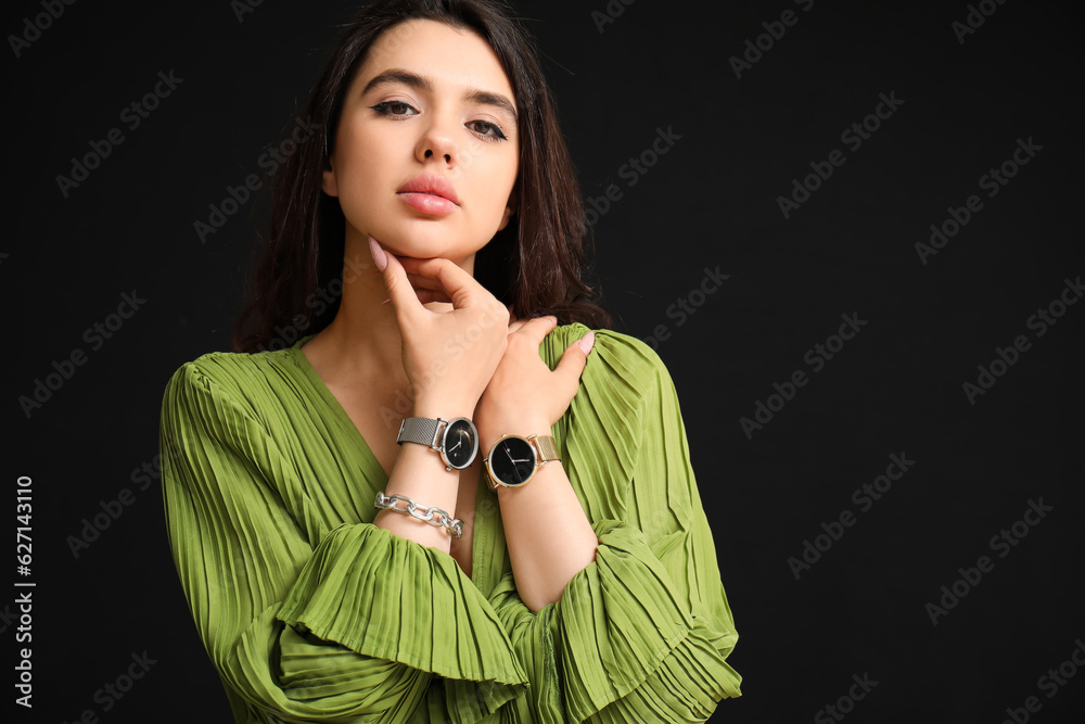 Beautiful young woman with wristwatches on black background