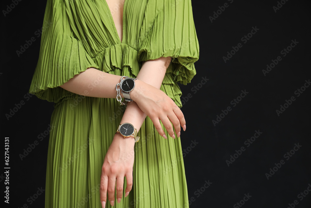 Elegant young woman with wristwatches on black background