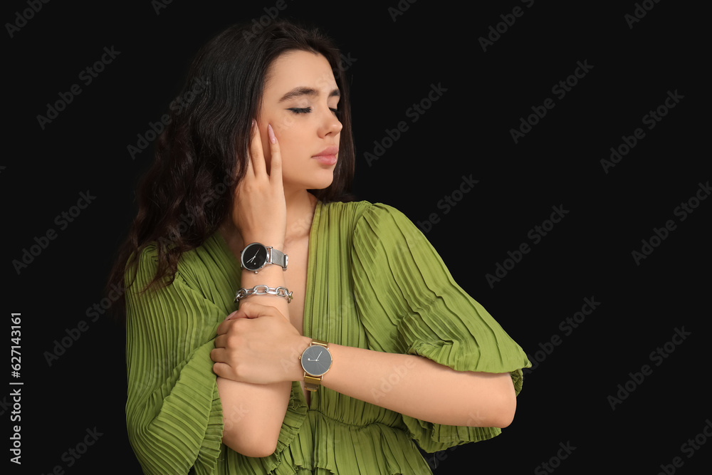 Beautiful young woman with wristwatches on black background