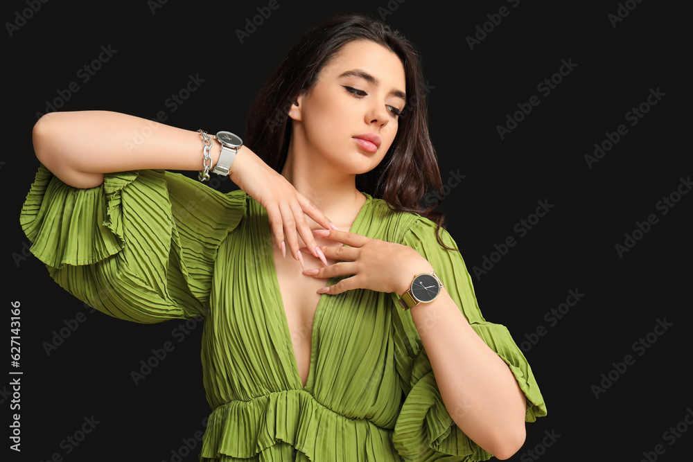 Beautiful young woman with wristwatches on black background