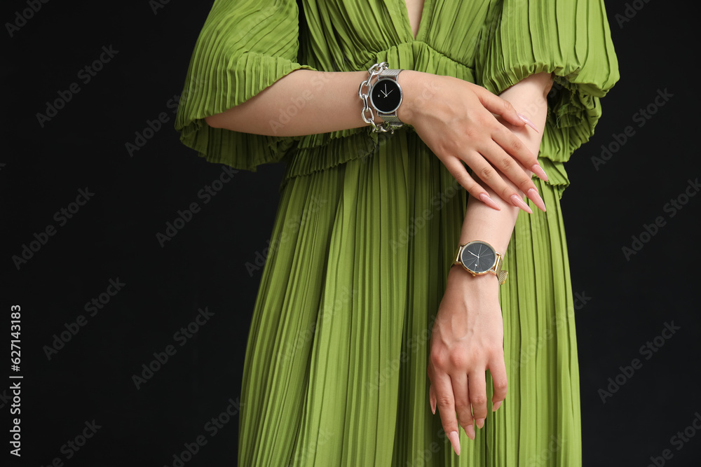 Elegant young woman with wristwatches on black background