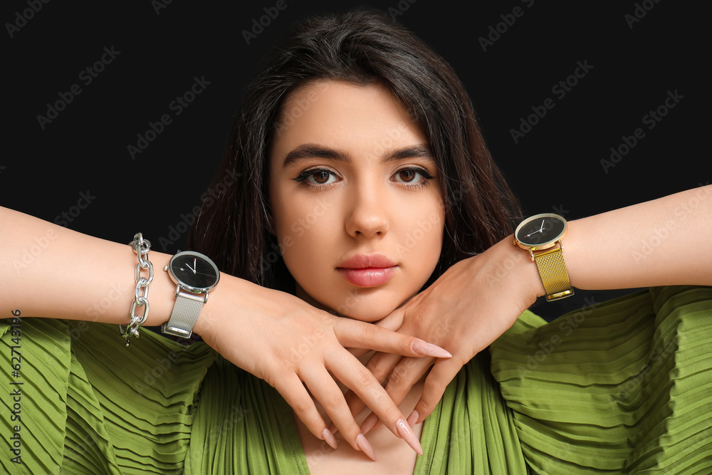 Beautiful young woman with wristwatches on black background