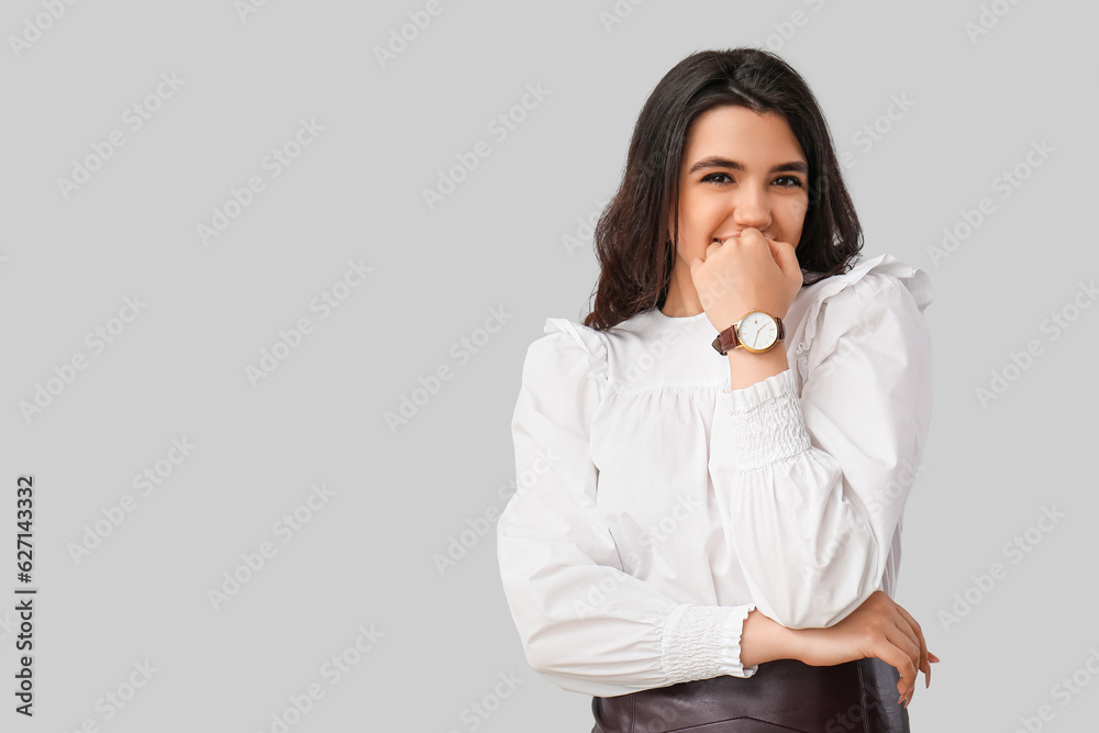 Beautiful young woman with wristwatch on grey background