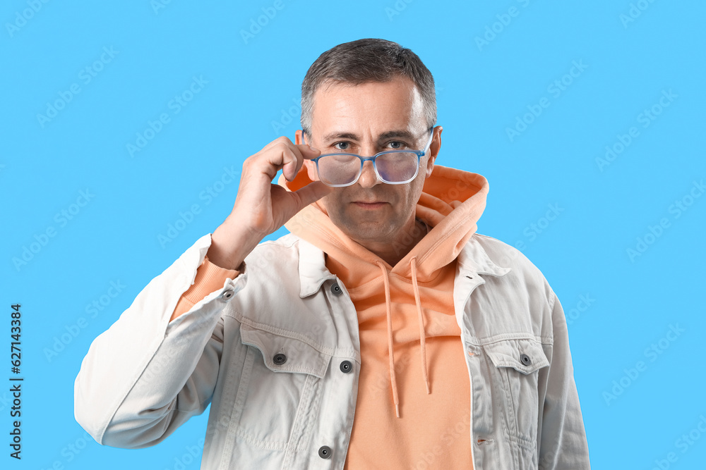 Mature man in eyeglasses on blue background