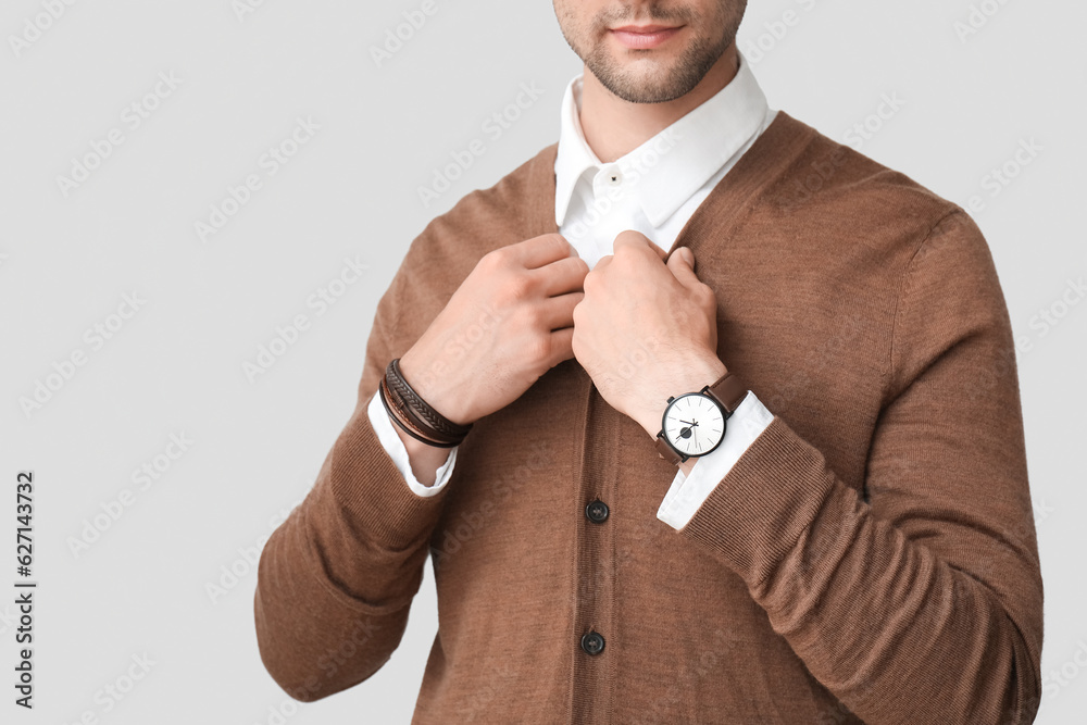 Stylish young man with wristwatch on grey background, closeup