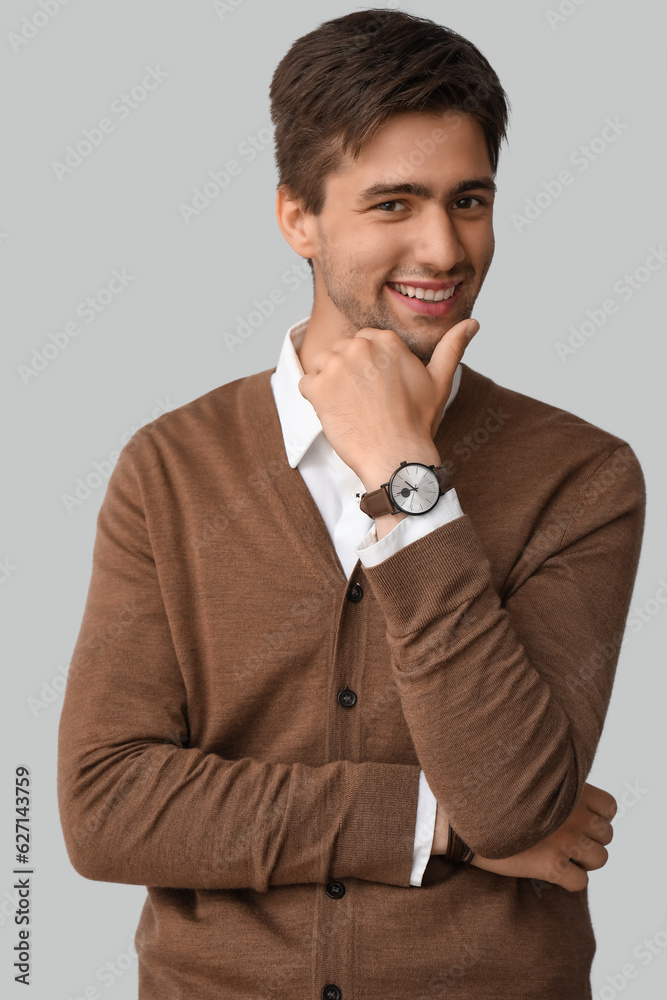 Handsome happy young man with wristwatch on grey background