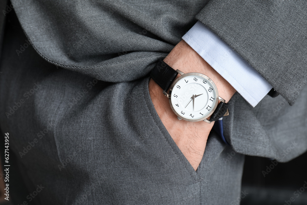 Stylish young man in suit with wristwatch, closeup