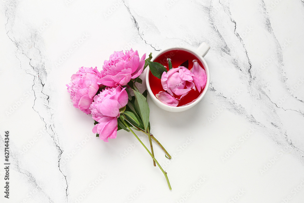 Cup of tea and beautiful peony flowers on light background