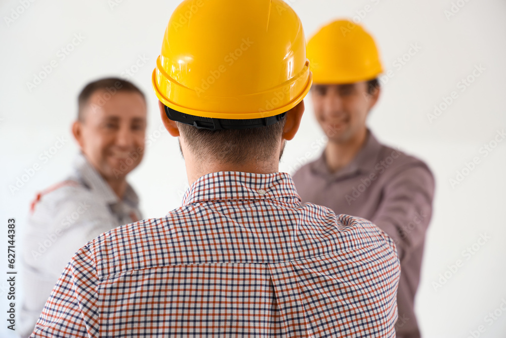 Team of male builders working in room, back view