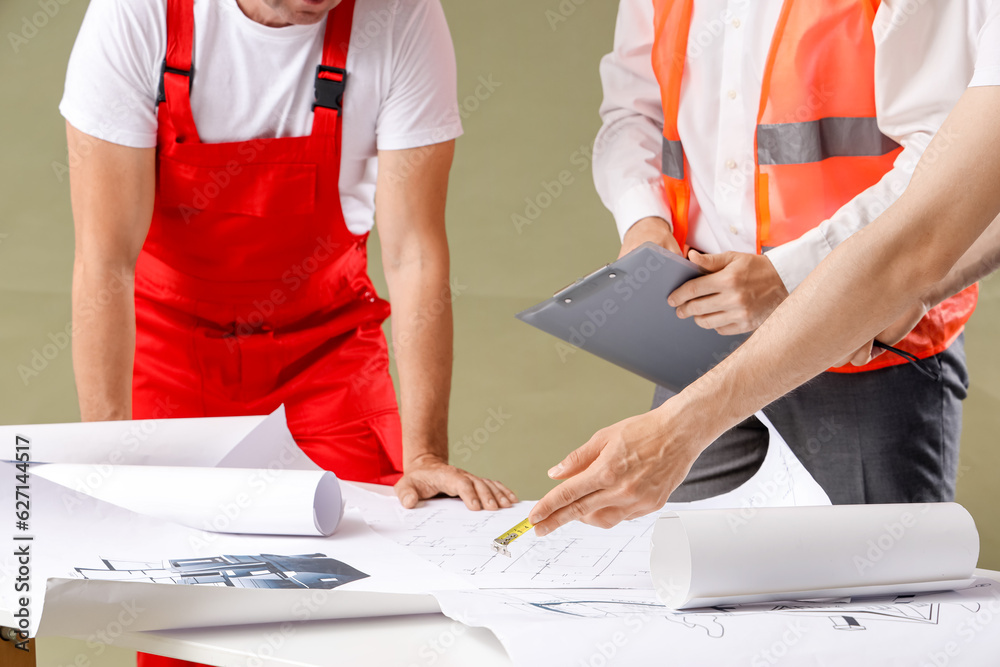 Team of male builders with table on green background, closeup