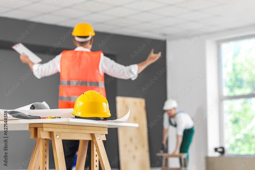 Table with builders hardhat and supplies in room, closeup