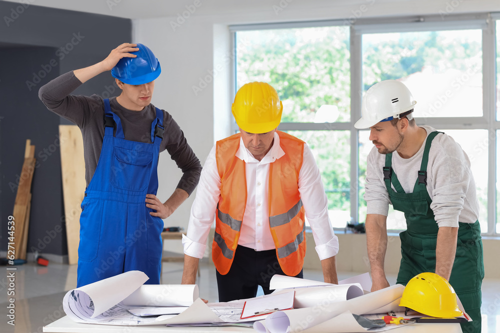 Team of male builders working in room