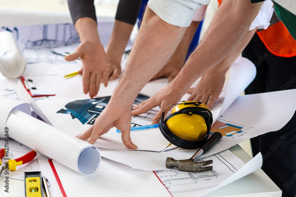 Team of male builders working with house plan in room, closeup