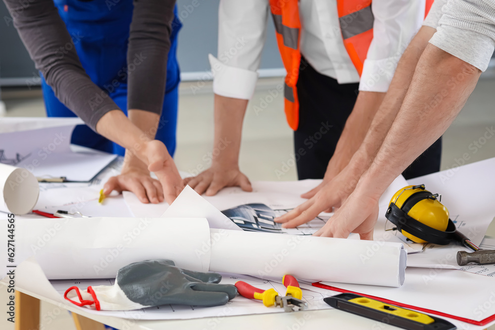 Team of male builders working with house plan in room, closeup