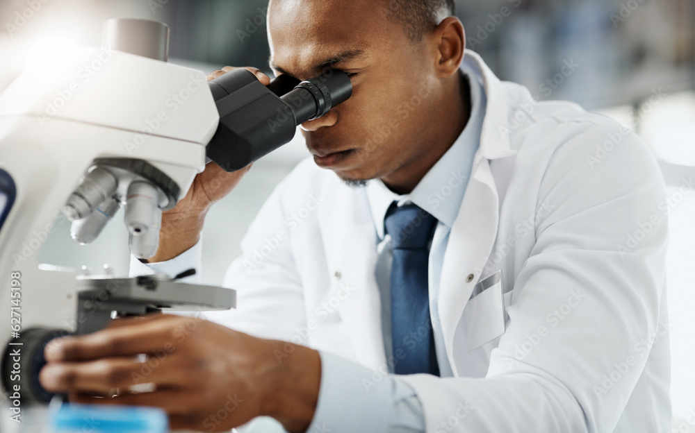 Looking closer...Cropped portrait of a handsome young male scientist using a microscope while doing 