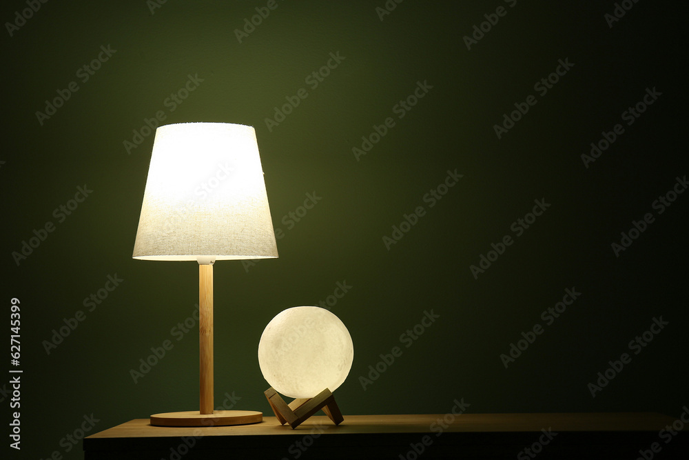 Different glowing lamps on wooden table in dark room