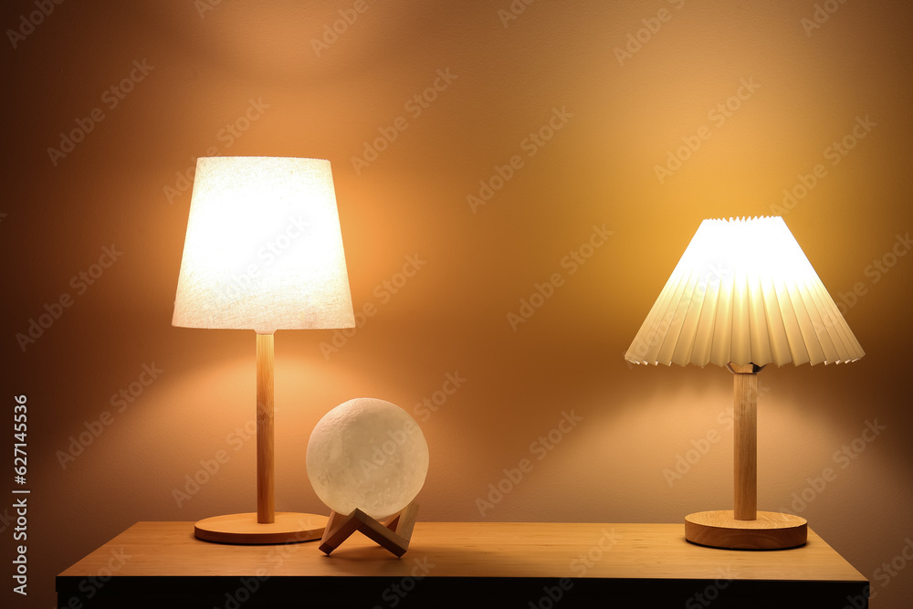 Different glowing lamps on wooden table in dark room