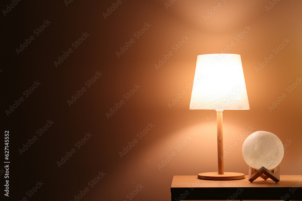 Different glowing lamps on wooden table in dark room