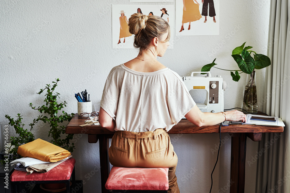 Beautiful things come together one stitch at a time. Rearview shot of a fashion designer working in 