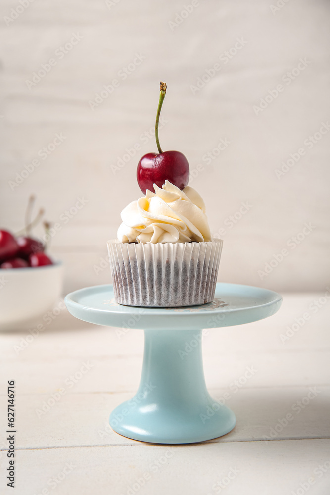 Stand with tasty cherry cupcake on table