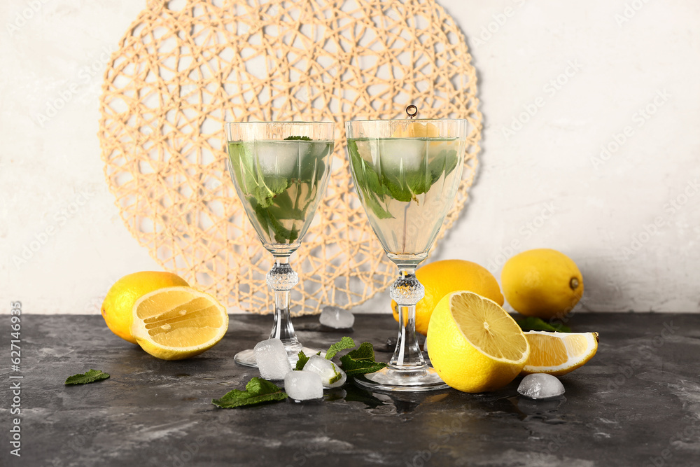 Glasses of cold mojito and lemons on dark table