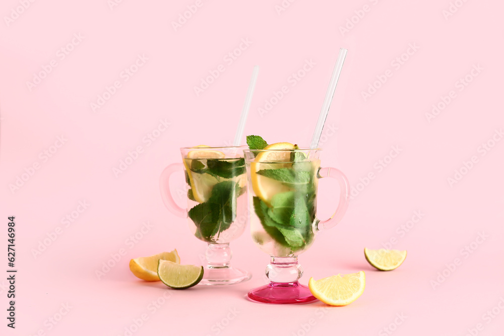 Glasses of cold mojito and citrus fruits on pink background