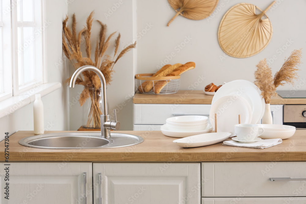 Sink and set of clean dishes on wooden countertop in kitchen