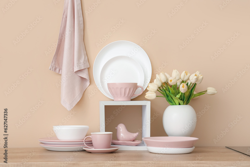 Set of clean dishes and vase with tulip flowers on wooden countertop