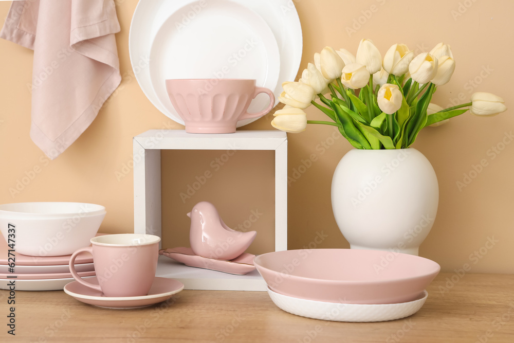 Set of clean dishes and vase with tulip flowers on wooden countertop