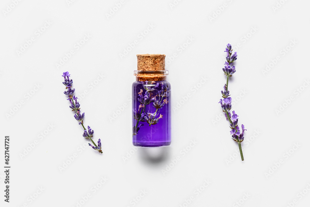 Bottle of essential oil and lavender flowers isolated on white background