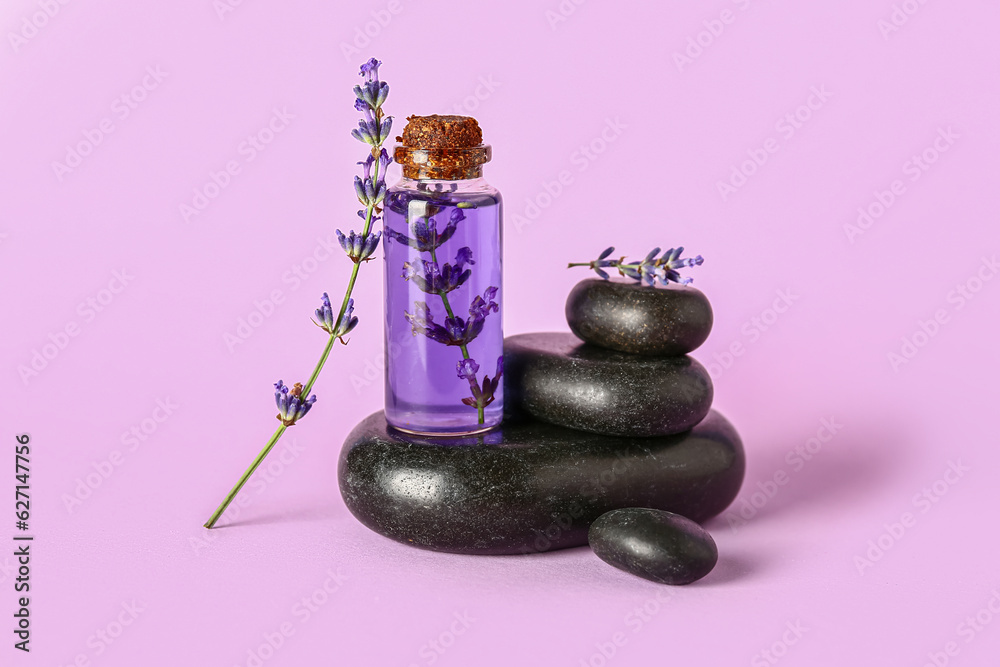 Composition with bottle of lavender essential oil and spa stones on color background