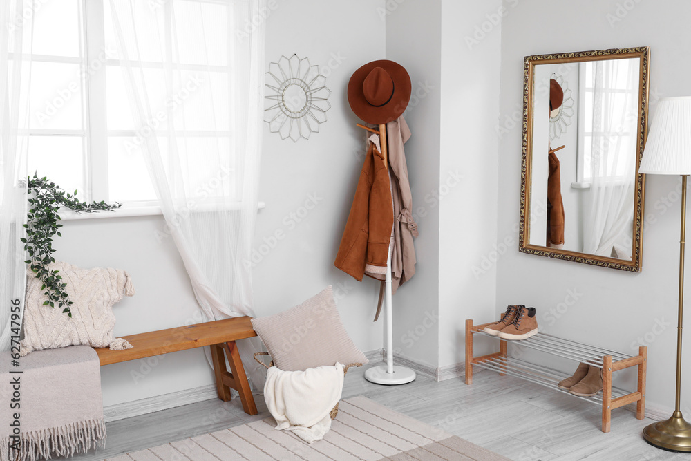 Interior of light hallway with mirror, rack and shoes stand