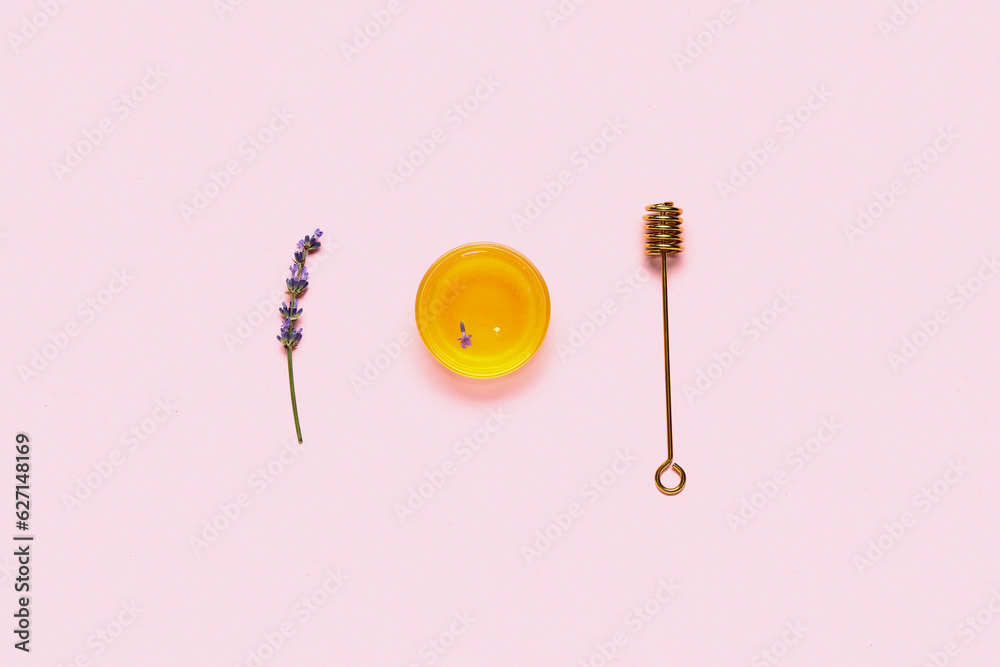 Glass bowl of sweet lavender honey and dipper on pink background