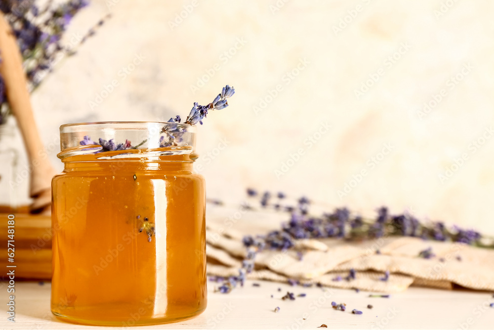 Jar of sweet lavender honey and flowers on white wooden table