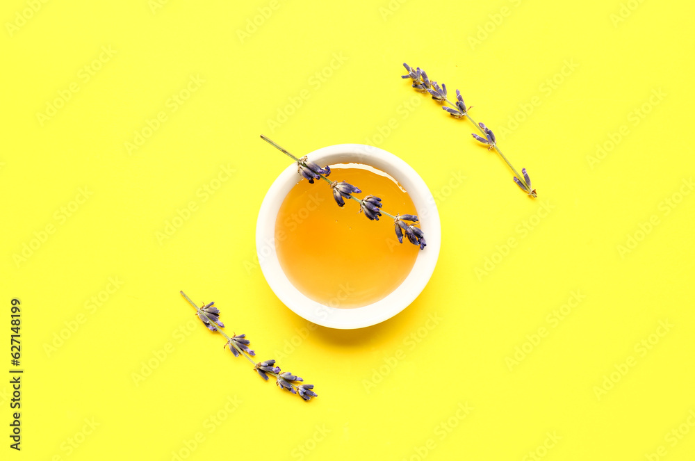 Bowl of sweet lavender honey and flowers on yellow background