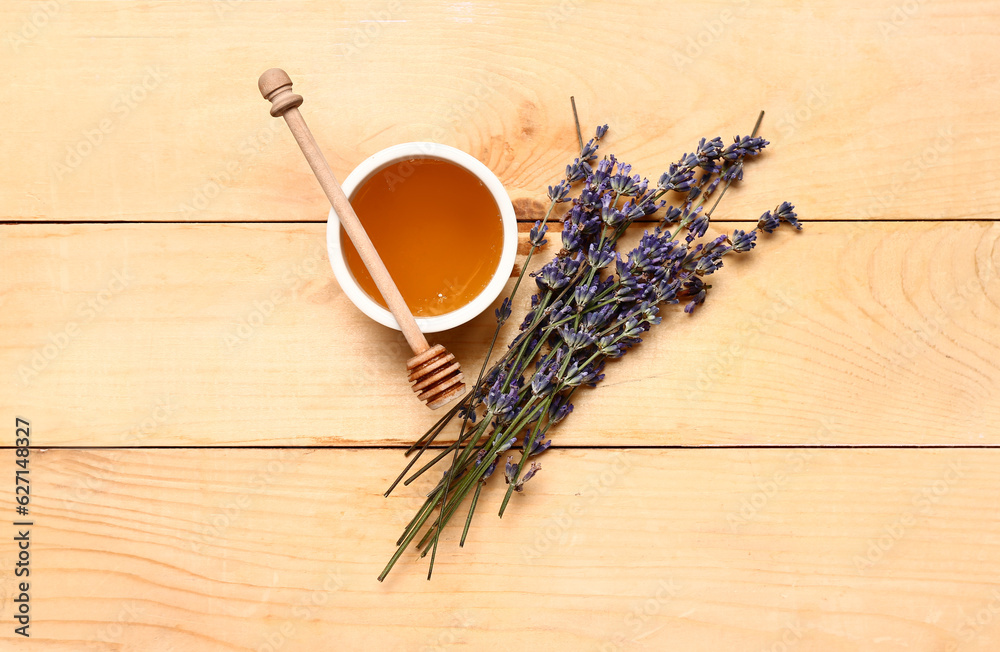 Bowl of sweet lavender honey, dipper and flowers on wooden background