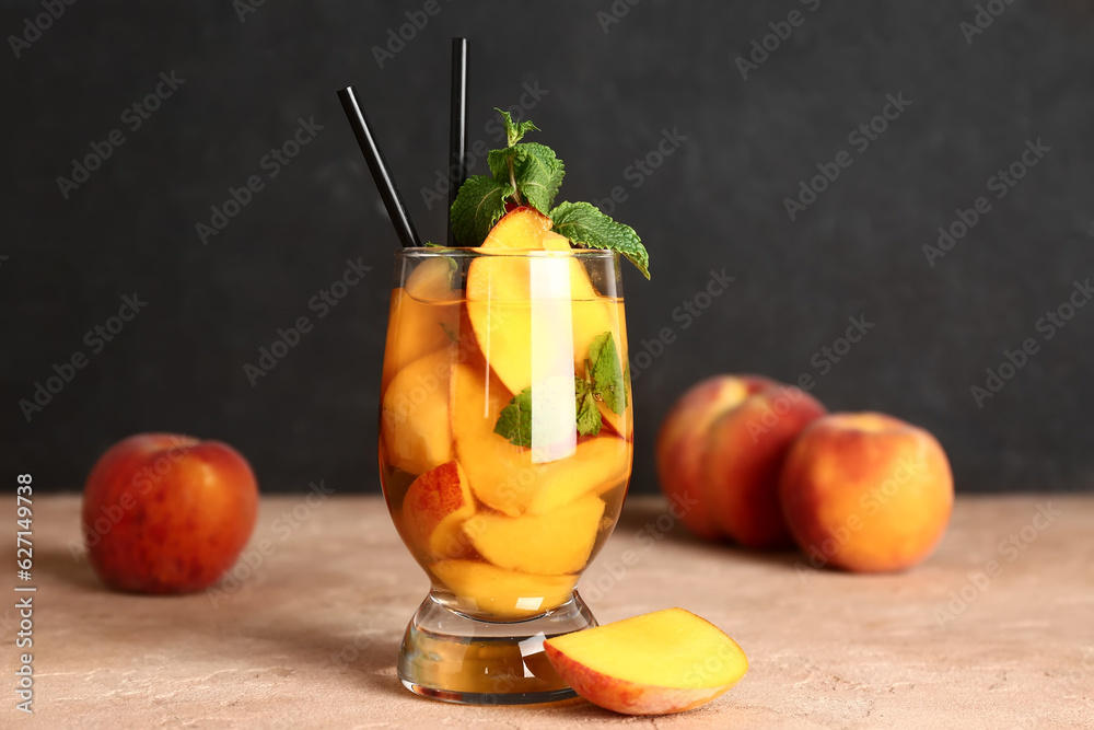 Glass of fresh peach lemonade with mint on pink table