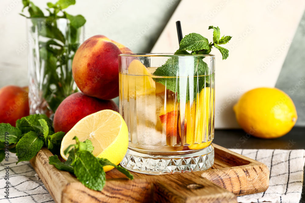 Glass of fresh peach lemonade with mint on black table