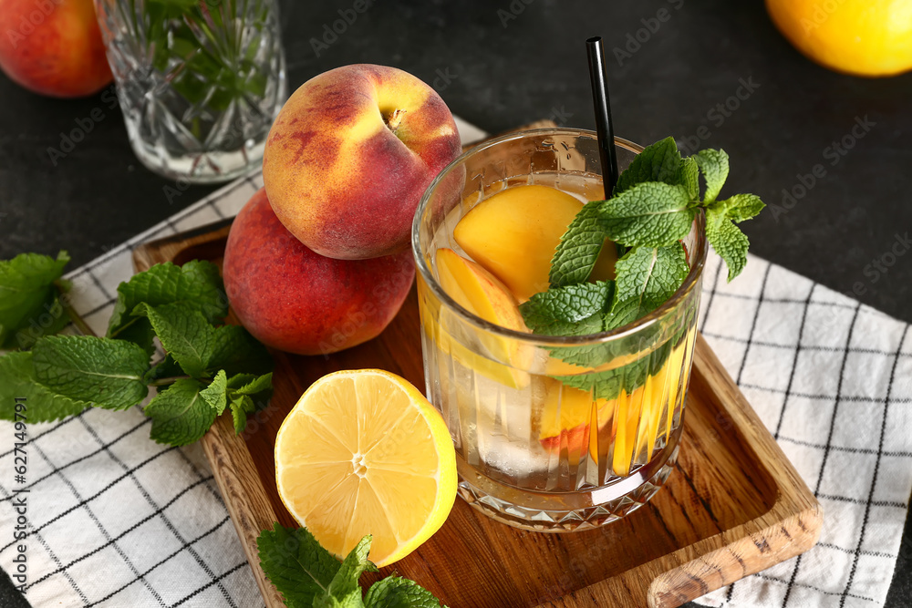 Glass of fresh peach lemonade with mint on black table